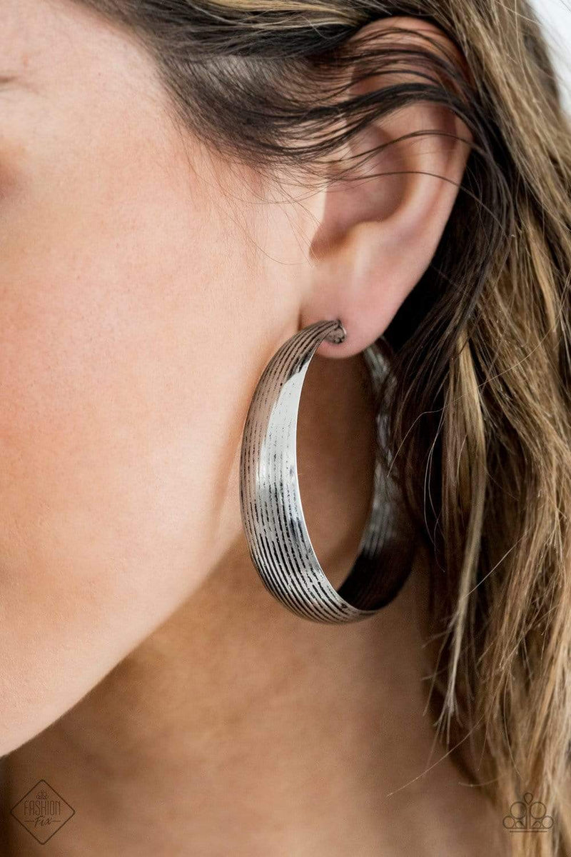 Lined in antiqued ridges, a thick silver hoop curls around the ear for an authentically rustic look. Earring attaches to a standard post fitting. Hoop measures approximately 2 ¼” in diameter.
