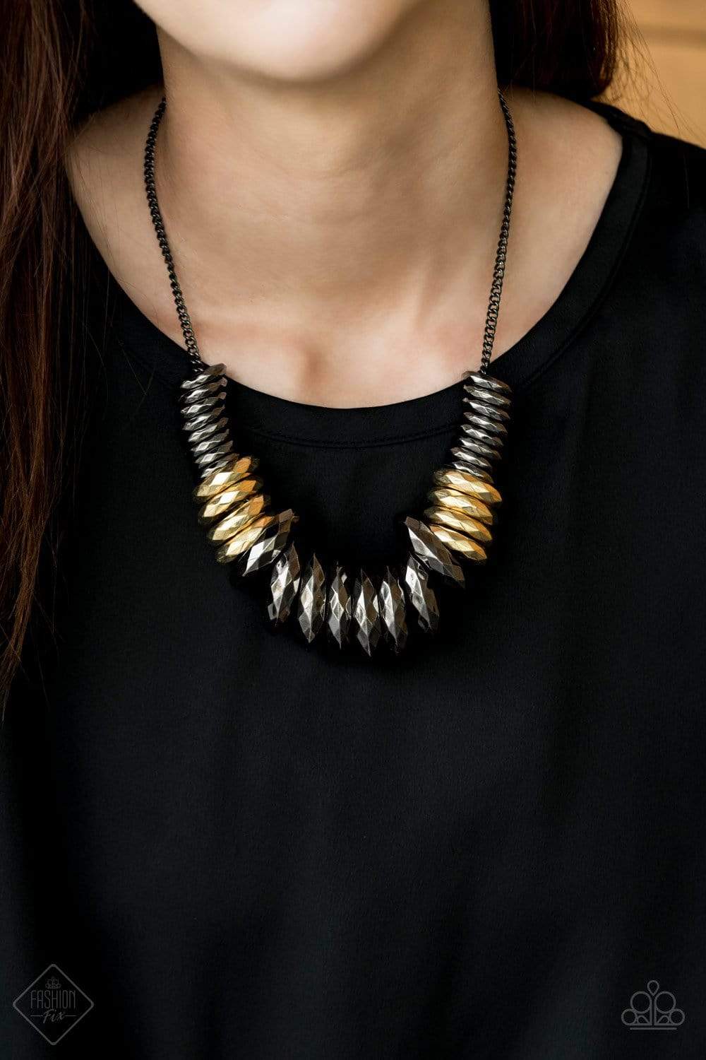 Gradually increasing in size, a collision of faceted gunmetal and gold rings slides along a classic gunmetal chain below the collar, creating a bold industrial statement piece. Features an adjustable clasp closure.