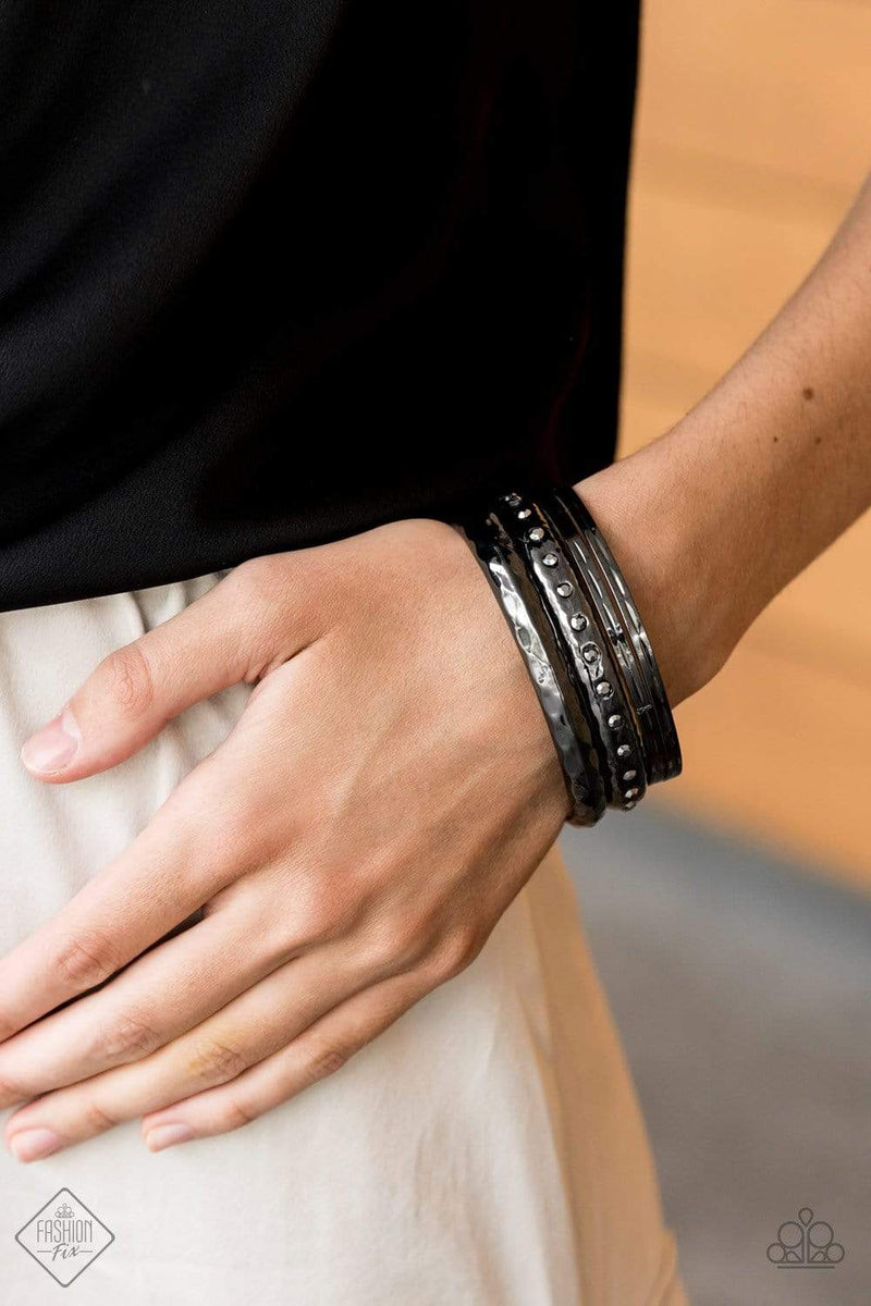 A stack of gunmetal bangles is hammered in texture, creating light-catching edges that reflect an immense amount of shine. One bangle is lined with glassy white rhinestones, adding a hint of twinkle